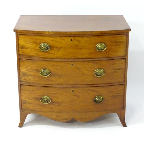 1938 - A late Georgian mahogany chest of drawers with a bow front above three long drawers with brass embos... 
