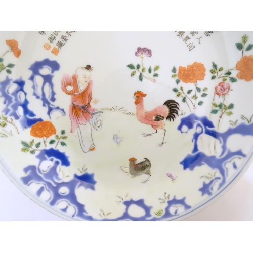 5 - A Chinese famille rose plate decorated with a figure, a cockerel, hen and chicks in a garden with fl... 