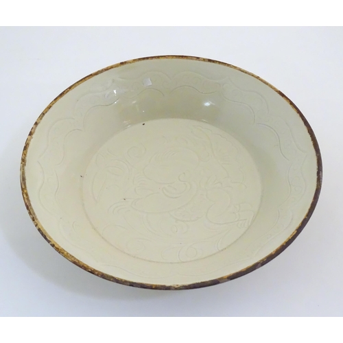 7 - A Chinese Ding style dished plate with relief decoration depicting a stylised baby. Approx. 8