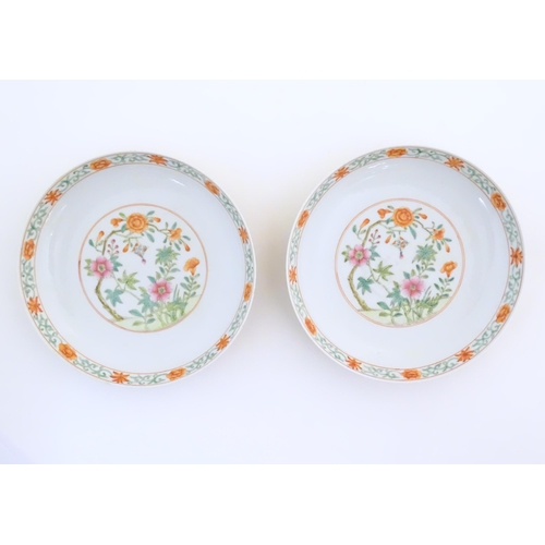 22 - A pair of Chinese plates / dishes with central roundels depicting flowers and a foliate border. The ... 