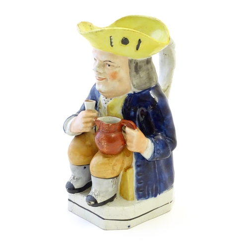 86A - A Toby jug modelled as a seated man holding a beaker and a jug, with moulded caryatid handle. Approx... 