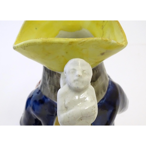 86A - A Toby jug modelled as a seated man holding a beaker and a jug, with moulded caryatid handle. Approx... 