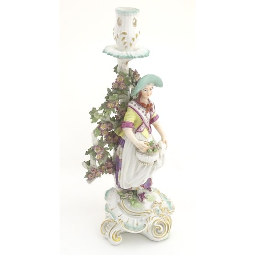 95 - A 19thC candlestick bocage figure, depicting a woman with a basket of flowers raised on a scrolling ... 