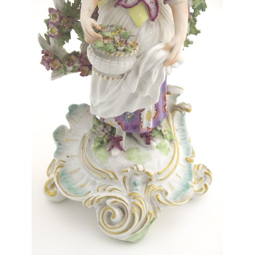 95 - A 19thC candlestick bocage figure, depicting a woman with a basket of flowers raised on a scrolling ... 