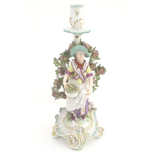 95 - A 19thC candlestick bocage figure, depicting a woman with a basket of flowers raised on a scrolling ... 