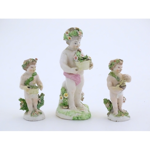 103 - Three Derby Porcelain style figures modelled as cherubs / young boys, two carrying baskets of flower... 