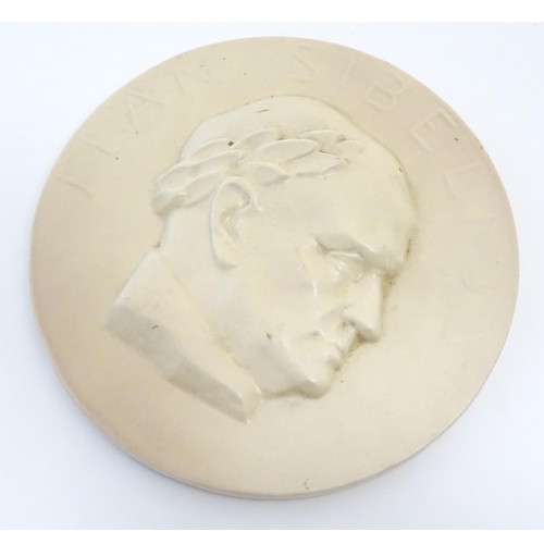 160 - A 20thC Arabia ceramic roundel / plaque depicting a portrait of the Finnish composer Jean Sibelius w... 