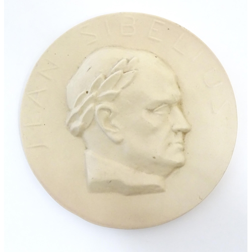 160 - A 20thC Arabia ceramic roundel / plaque depicting a portrait of the Finnish composer Jean Sibelius w... 