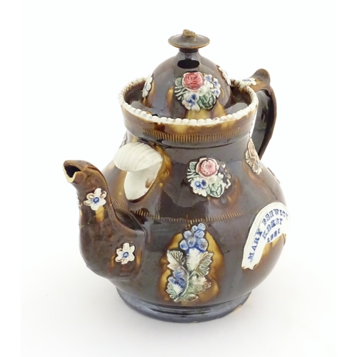 179 - A Victorian treacle glazed bargeware teapot with applied floral decoration and a banner for Mary Fen... 