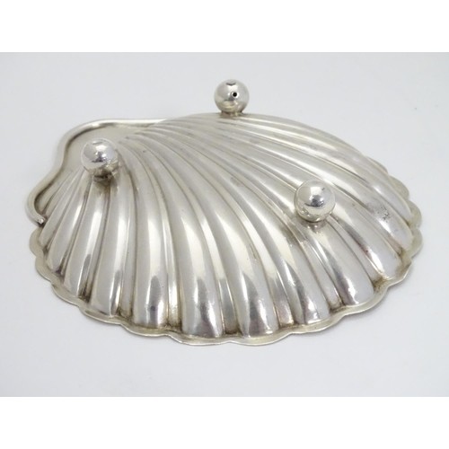 358 - A silver scallop-shaped dish raised on three bun feet. Hallmarked Sheffield 1910 maker Harrison Brot... 