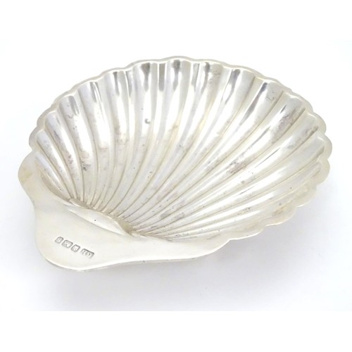 358 - A silver scallop-shaped dish raised on three bun feet. Hallmarked Sheffield 1910 maker Harrison Brot... 