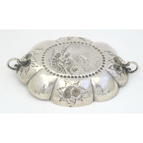 492 - A Continental silver dish of lobed form with twin handles and embossed decoration. Indistinctly mark... 