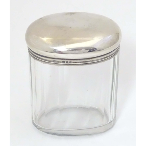 495 - A glass dressing table jar of oval form with facet detail and silver top hallmarked London 1921 make... 