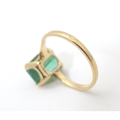 561 - A yellow metal ring set with baguette cut green stone. Ring size approx K 1/2