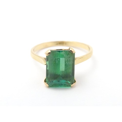 561 - A yellow metal ring set with baguette cut green stone. Ring size approx K 1/2