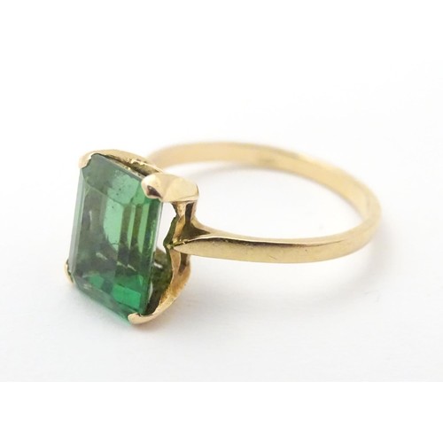 561 - A yellow metal ring set with baguette cut green stone. Ring size approx K 1/2