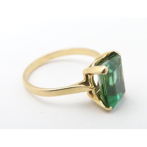 561 - A yellow metal ring set with baguette cut green stone. Ring size approx K 1/2