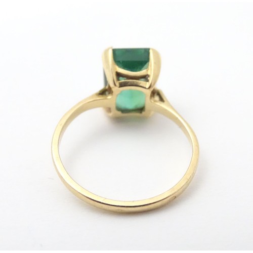 561 - A yellow metal ring set with baguette cut green stone. Ring size approx K 1/2