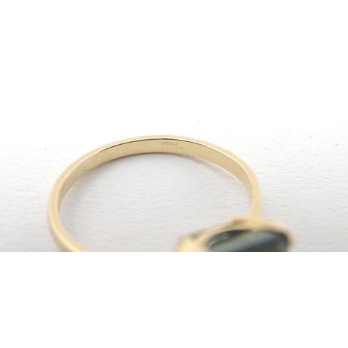 561 - A yellow metal ring set with baguette cut green stone. Ring size approx K 1/2