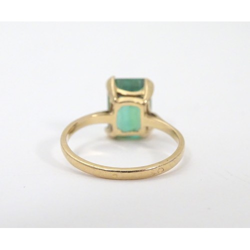 561 - A yellow metal ring set with baguette cut green stone. Ring size approx K 1/2