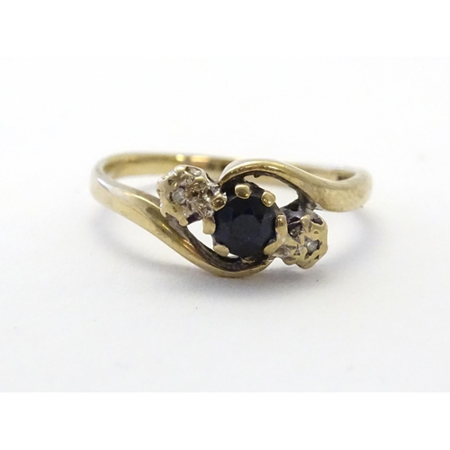 585 - A 9ct gold ring set with central blue spinel flanked by diamonds. Ring size approx. N