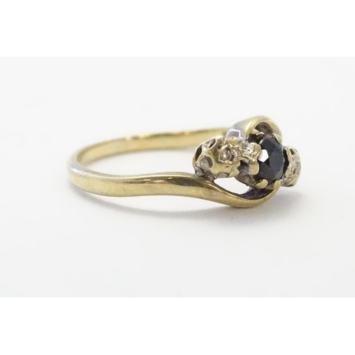 585 - A 9ct gold ring set with central blue spinel flanked by diamonds. Ring size approx. N