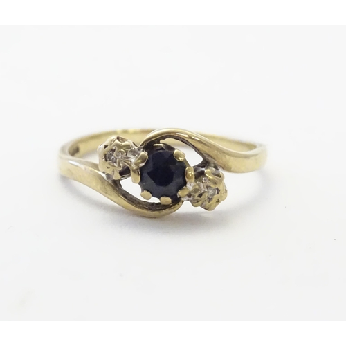 585 - A 9ct gold ring set with central blue spinel flanked by diamonds. Ring size approx. N