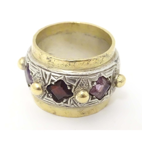 586 - A silver dress ring with gilt detail, set with amethysts and garnet, hallmarked London 1989, maker M... 