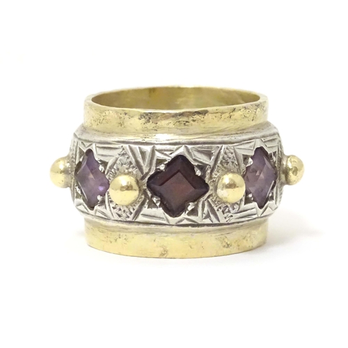 586 - A silver dress ring with gilt detail, set with amethysts and garnet, hallmarked London 1989, maker M... 