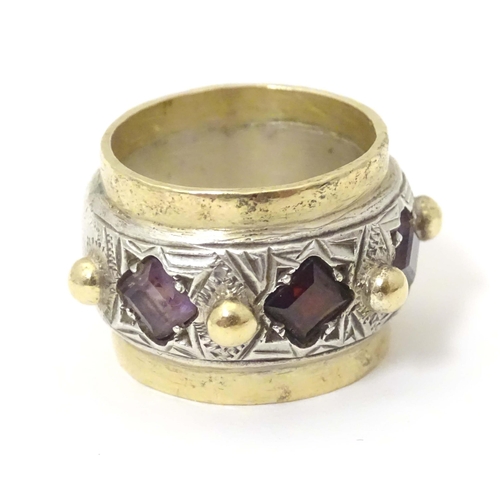 586 - A silver dress ring with gilt detail, set with amethysts and garnet, hallmarked London 1989, maker M... 