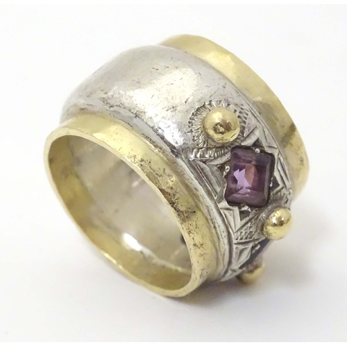 586 - A silver dress ring with gilt detail, set with amethysts and garnet, hallmarked London 1989, maker M... 