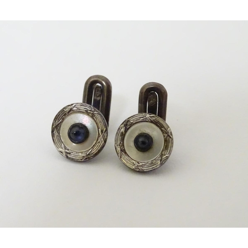 747A - A pair of dress studs marked 900 and set with sapphire cabochon to centre. 1/4