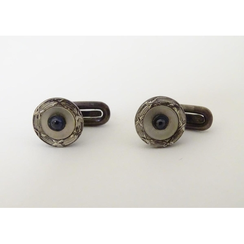 747A - A pair of dress studs marked 900 and set with sapphire cabochon to centre. 1/4