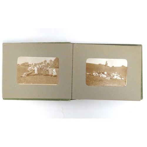 963 - An early 20thC photograph album with sepia and monochrome photos to include group shots in the count... 