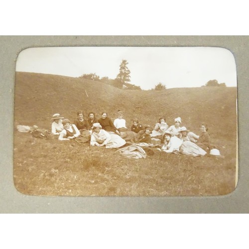 963 - An early 20thC photograph album with sepia and monochrome photos to include group shots in the count... 