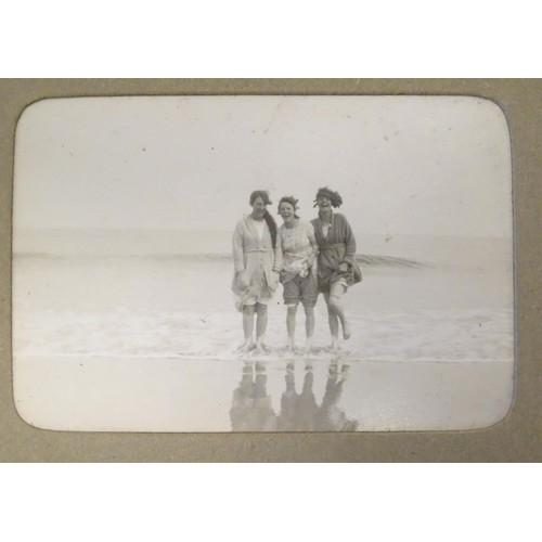 963 - An early 20thC photograph album with sepia and monochrome photos to include group shots in the count... 