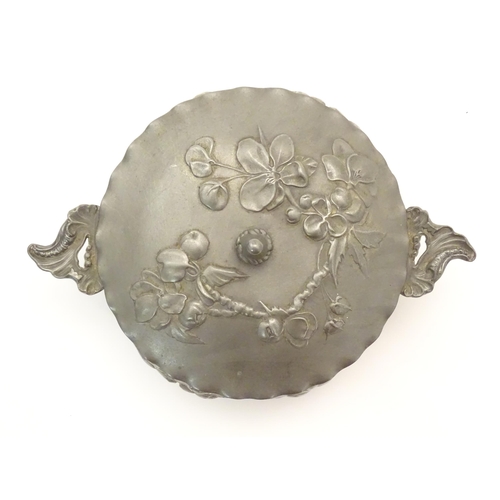 1001 - An Art Nouveau / Jugendstil twin handled pewter pot and cover with relief floral and foliage decorat... 