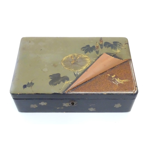 1047 - A Japanese lacquered box with hinge lid decorated with flowers and foliage, with faux lifted corner ... 