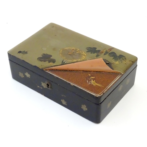 1047 - A Japanese lacquered box with hinge lid decorated with flowers and foliage, with faux lifted corner ... 