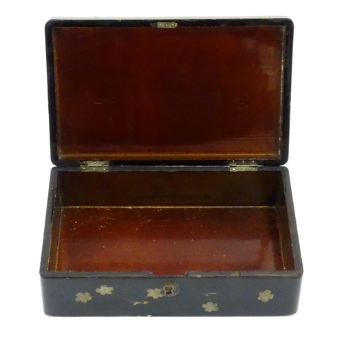 1047 - A Japanese lacquered box with hinge lid decorated with flowers and foliage, with faux lifted corner ... 