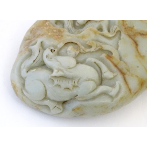 1053 - A Chinese jade scroll weight with carved decoration depicting a dragon and horse. Approx. 5