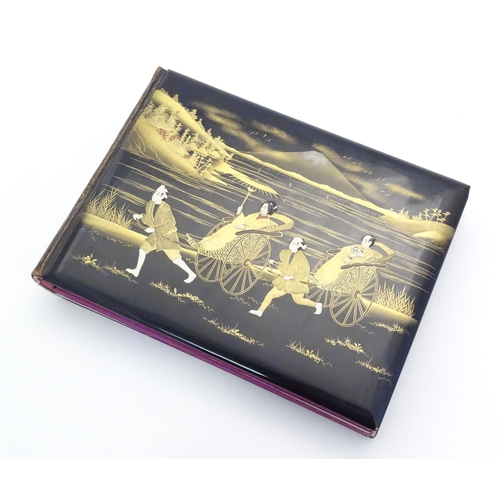 1054 - A Japanese photograph album with lacquered boards, the cover decorated with figures travelling by ha... 