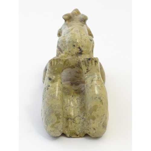 1056 - A 20thC soapstone model of a stylised figure lying on their front with a stylised rabbit / animal on... 