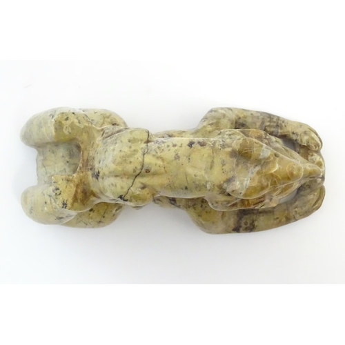 1056 - A 20thC soapstone model of a stylised figure lying on their front with a stylised rabbit / animal on... 