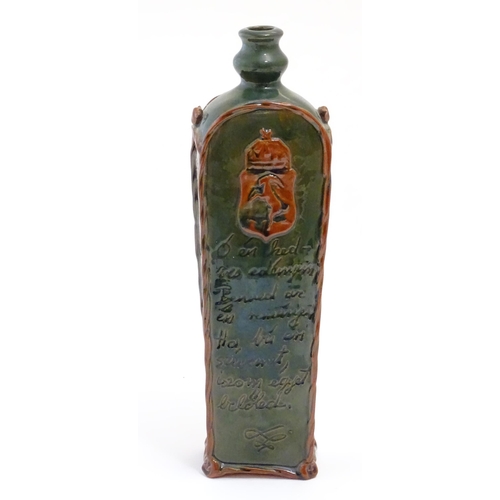 1096 - A Continental terracotta gin / spirit bottle / flask of tapering form with a green glaze, incised sc... 