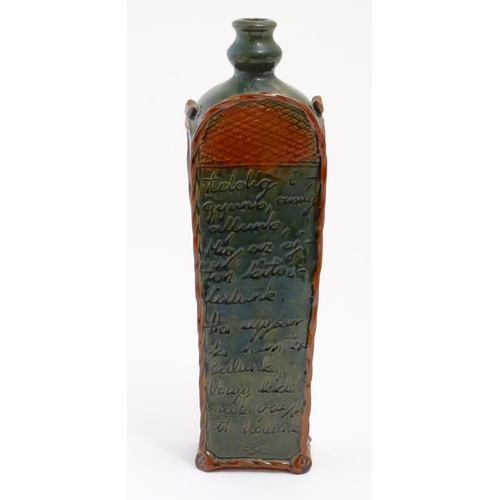 1096 - A Continental terracotta gin / spirit bottle / flask of tapering form with a green glaze, incised sc... 