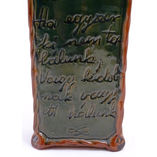 1096 - A Continental terracotta gin / spirit bottle / flask of tapering form with a green glaze, incised sc... 