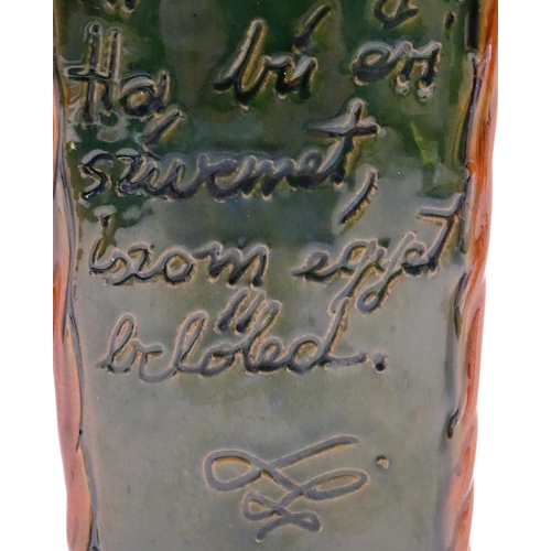 1096 - A Continental terracotta gin / spirit bottle / flask of tapering form with a green glaze, incised sc... 