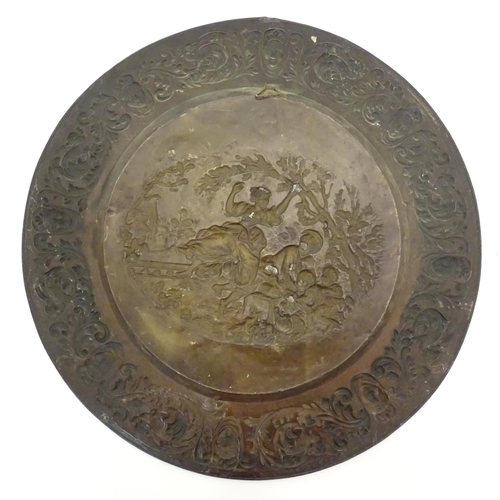 1272 - A large 20thC Continental embossed brass charger decorated with a bucolic central scene with figures... 