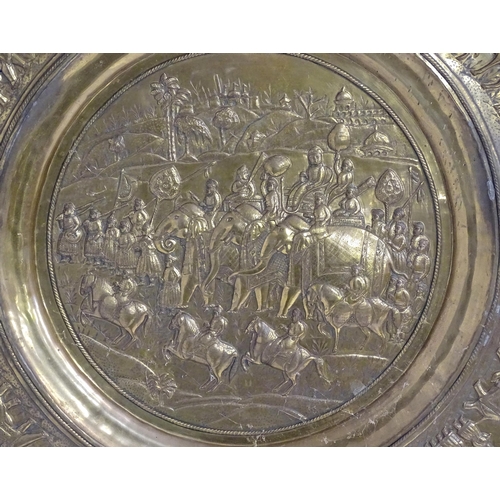 1273 - A large 20thC Indian brass charger with embossed decoration depicting an Indian procession with Impe... 